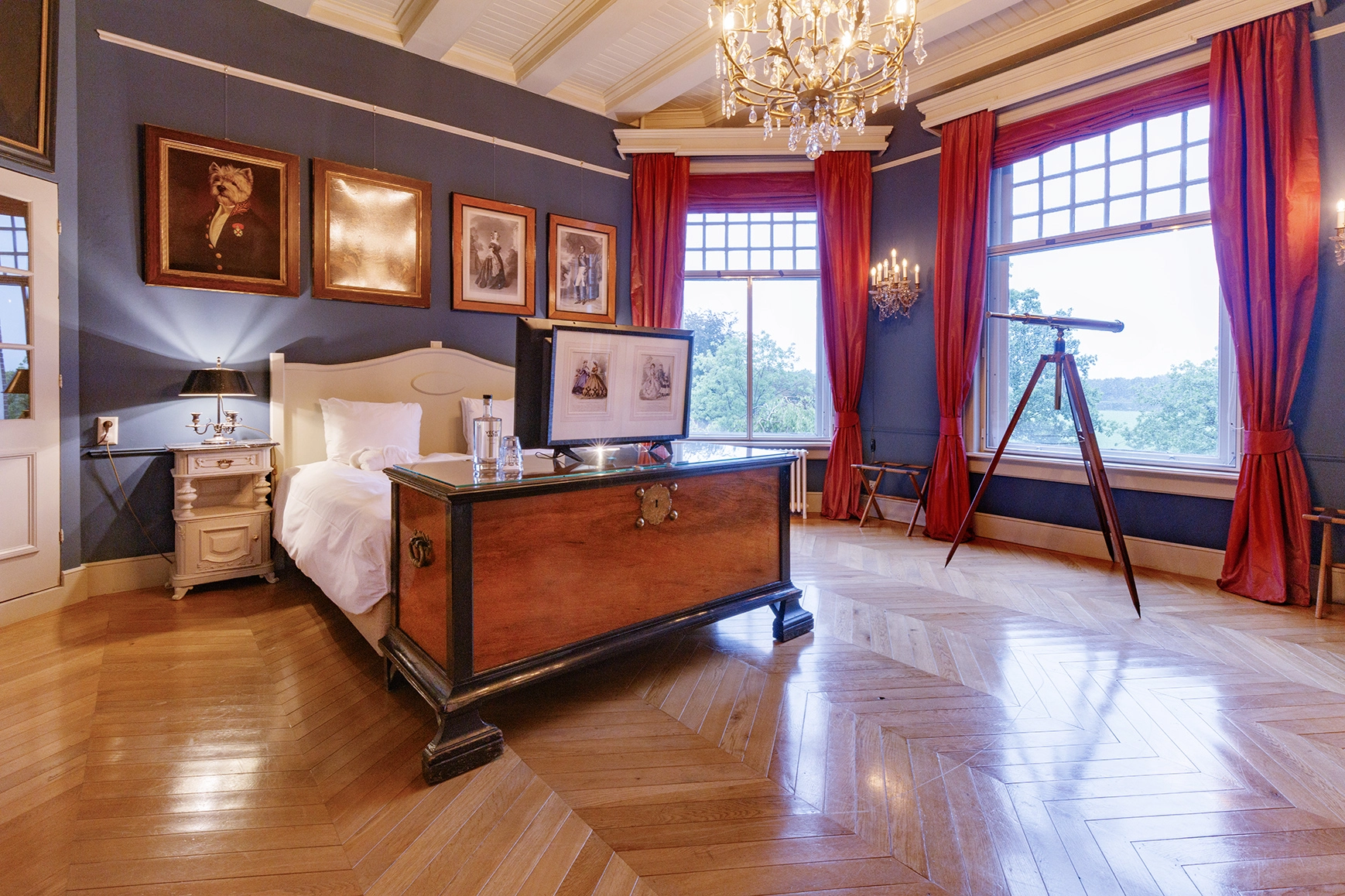 De portrait kamer bij Logement aan de Vecht. Met een bed en tv en rode gordijnen.