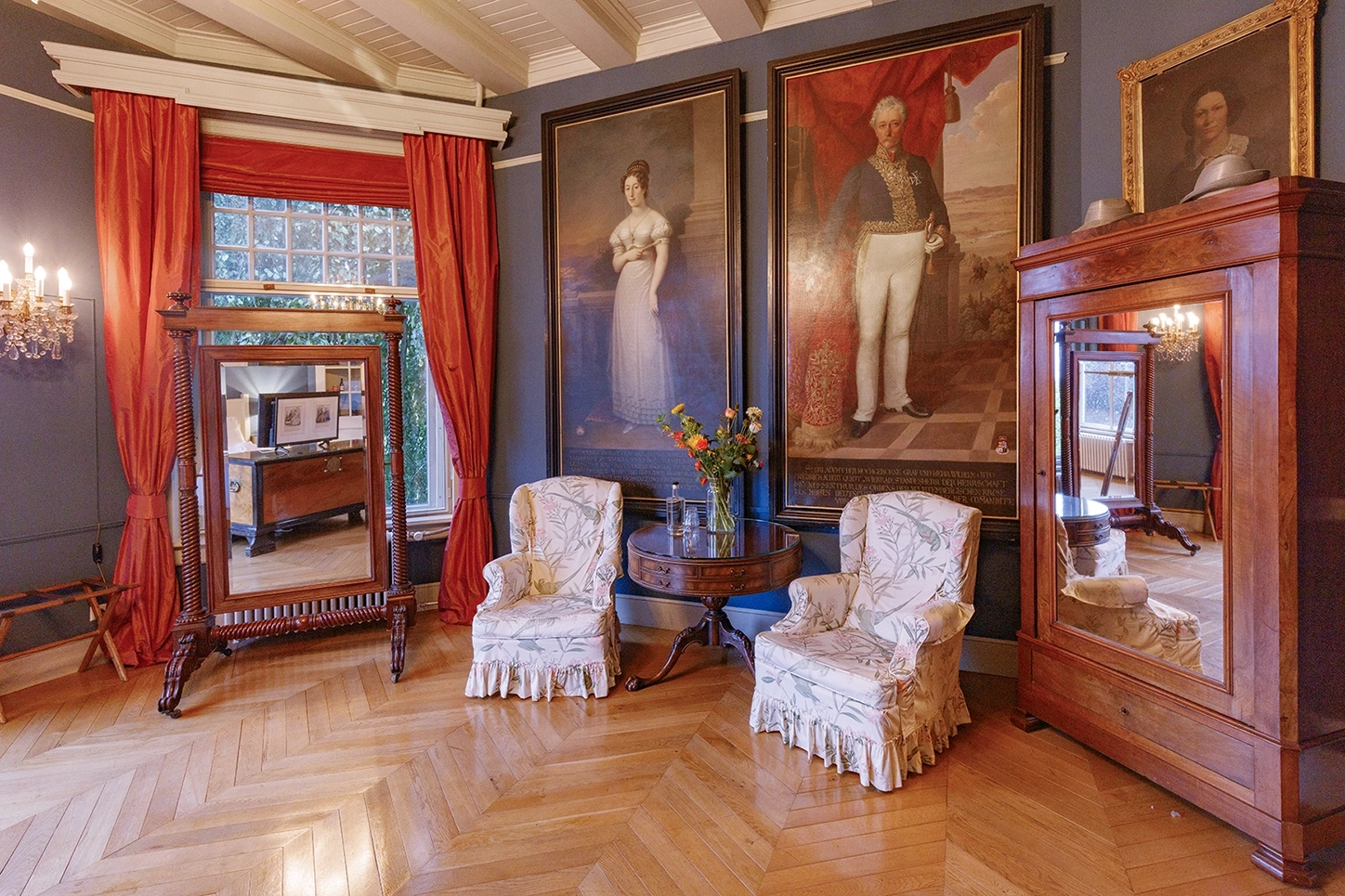 De portrait kamer bij Logement aan de Vecht. Een foto van twee witte stoelen en 2 grote schilderijen van een man en een vrouw.
