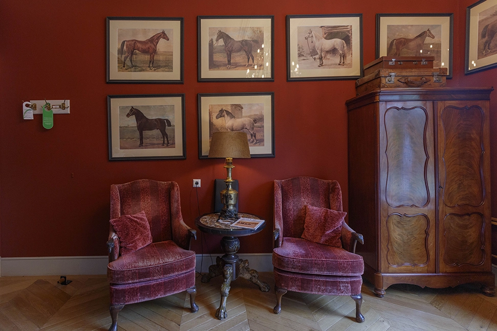 Logement aan de Vecht kamer mientje, met een rode muur en twee rode stoelen en een houten kast.